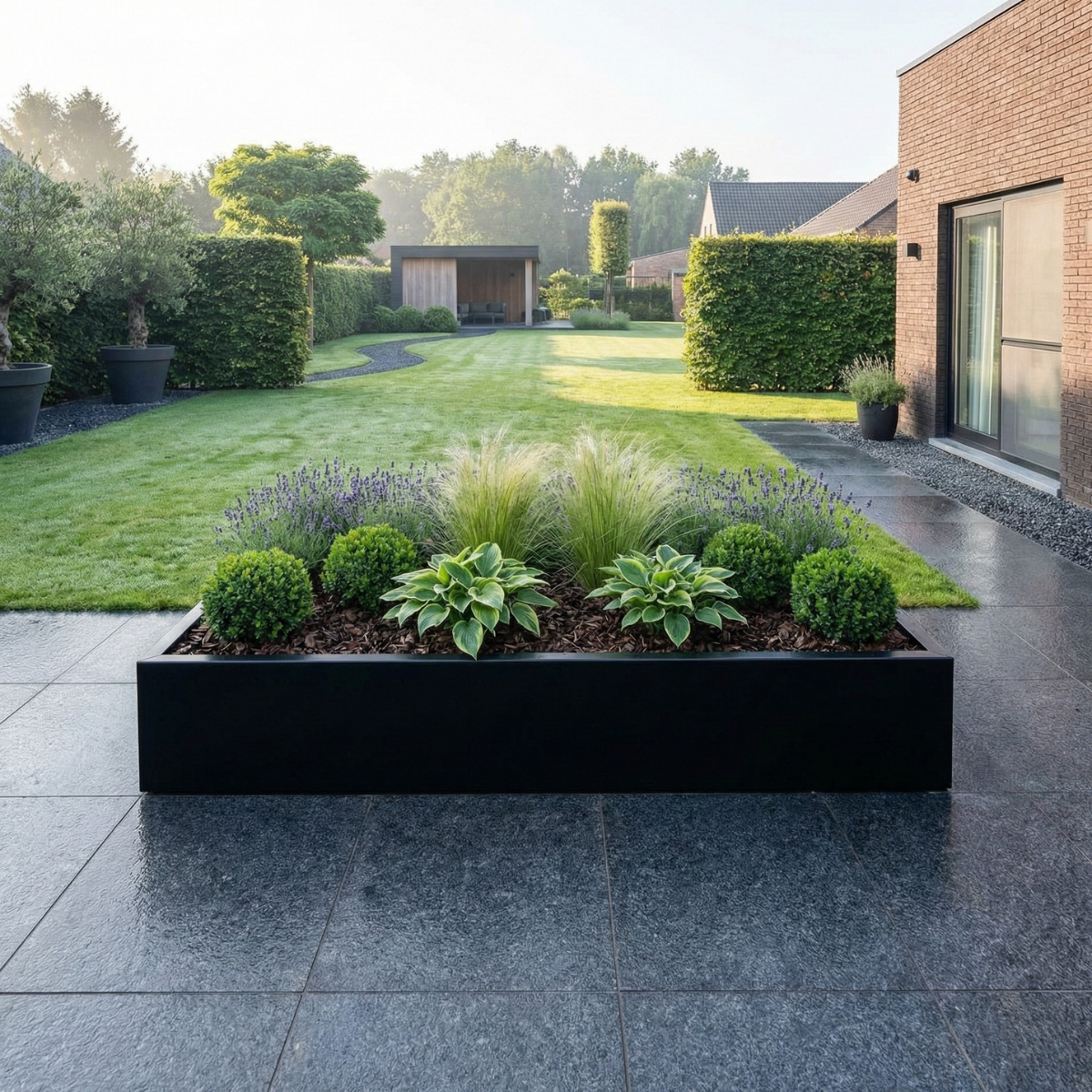 Grote zwarte rechthoekige plantenbak gevuld met buxusbollen, hosta's, lavendel en siergrassen op een terras van donkere tegels.