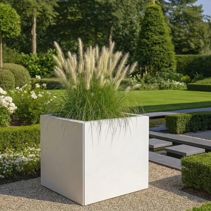 Twee grote antracietkleurige vierkante plantenbakken gevuld met boompjes op stam en paarse lavendel op een strakke betegelde oprit voor een modern wit huis.