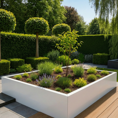 Grote witte rechthoekige plantenbak gevuld met siergrassen, lavendel en een klein boompje in een moderne tuin met een houten vlonder.